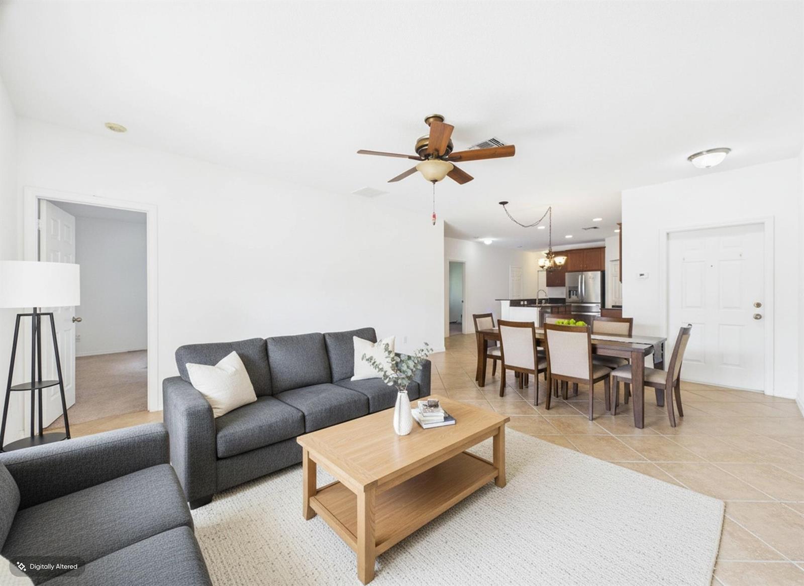 A living room with a gray sofa, wooden coffee table, and an adjacent dining area — 157 Blue Grotto Drive, Fort Pierce FL 34945, FORT PIERCE, FL