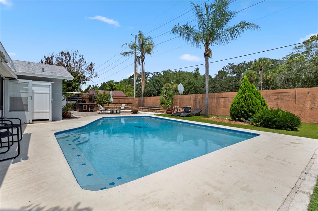 A backyard features a swimming pool, concrete patio, palm trees, and a wooden privacy fence — 961 APPLE LANE, ALTAMONTE SPRINGS, FL