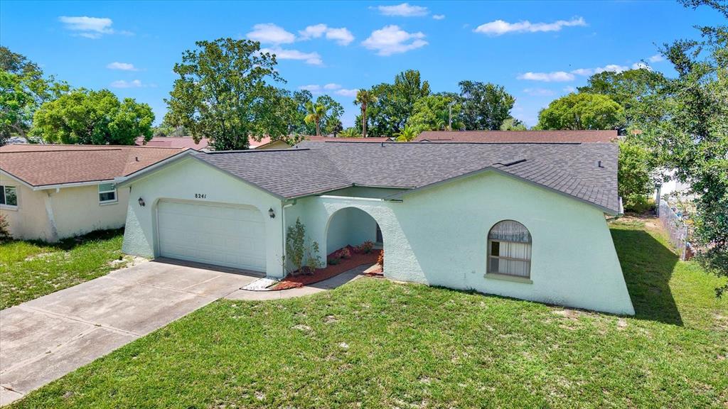 A light green, single-story house with a two-car garage and a front arched entryway — 8241 WINTHROP DRIVE, PORT RICHEY, FL