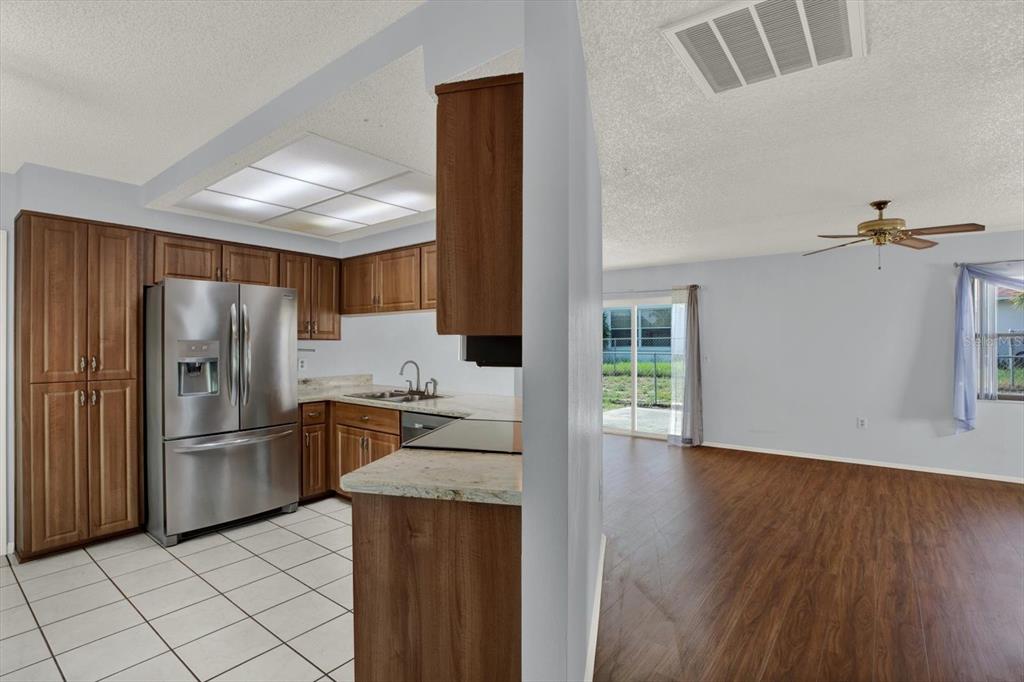 A kitchen with wood cabinets and stainless steel appliances opens to a living area — 8241 WINTHROP DRIVE, PORT RICHEY, FL