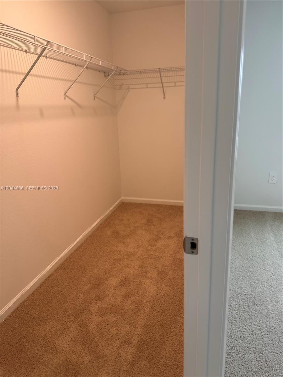 A walk-in closet features beige carpet and white wire shelving mounted on the walls — 25 Redbud Rd, Palm Coast FL 32137, PALM COAST, FL