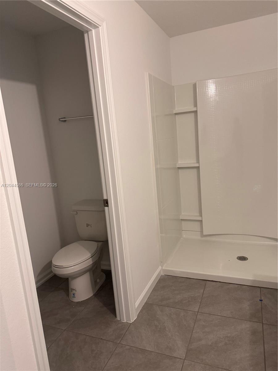 This bathroom features a walk-in shower with white walls and a separate toilet area — 25 Redbud Rd, Palm Coast FL 32137, PALM COAST, FL