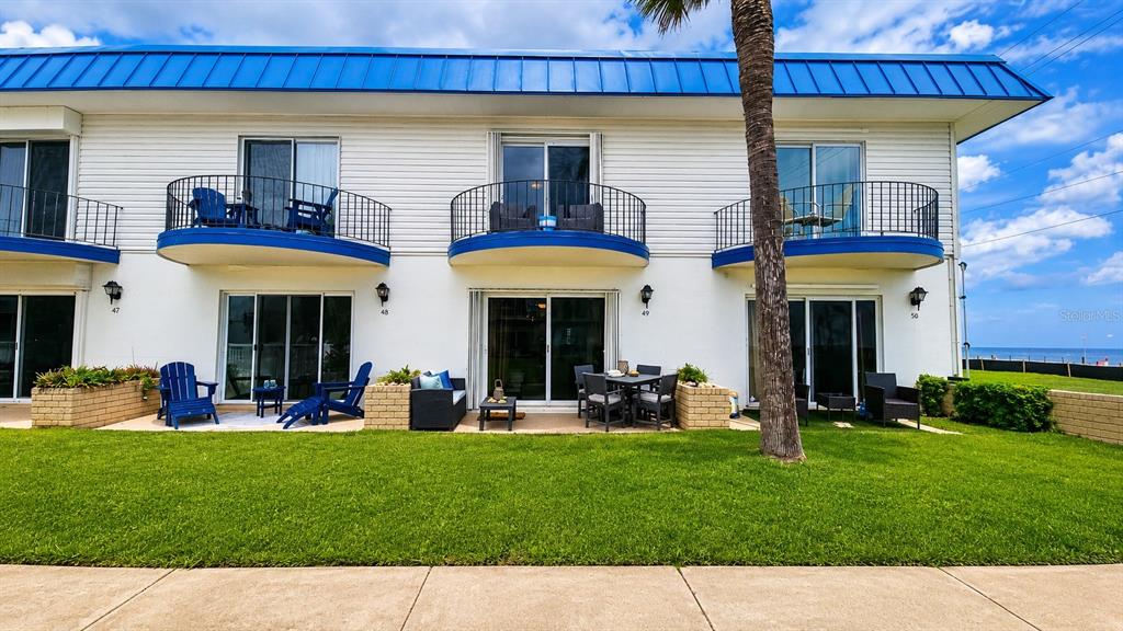 A two-story building with white siding, blue trim, and balconies overlooking a grassy lawn — 2750 OCEAN SHORE BOULEVARD UNIT 49, ORMOND BEACH, FL