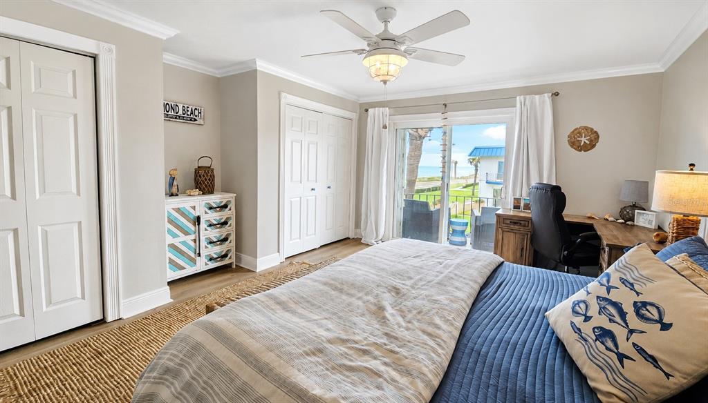 A bedroom features a bed, desk, dresser, and sliding glass doors opening to a balcony — 2750 OCEAN SHORE BOULEVARD UNIT 49, ORMOND BEACH, FL