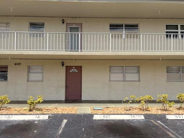 A two-story apartment building exterior features a brown door, white railings, and parking spaces — 607 S State Rd 7 # 1g, Margate FL 33068, MARGATE, FL