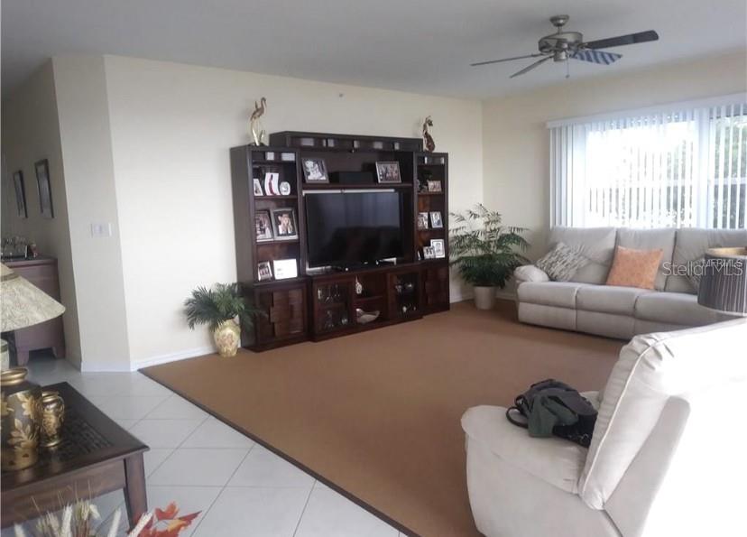 A living room features a large entertainment center, a beige sofa, and a ceiling fan — 200 HARBOR WALK DRIVE UNIT 321, PUNTA GORDA, FL