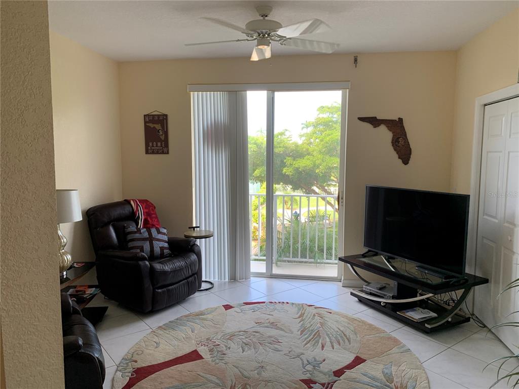 A living room features tile floors, a ceiling fan, a television, and a sliding glass door — 200 HARBOR WALK DRIVE UNIT 321, PUNTA GORDA, FL