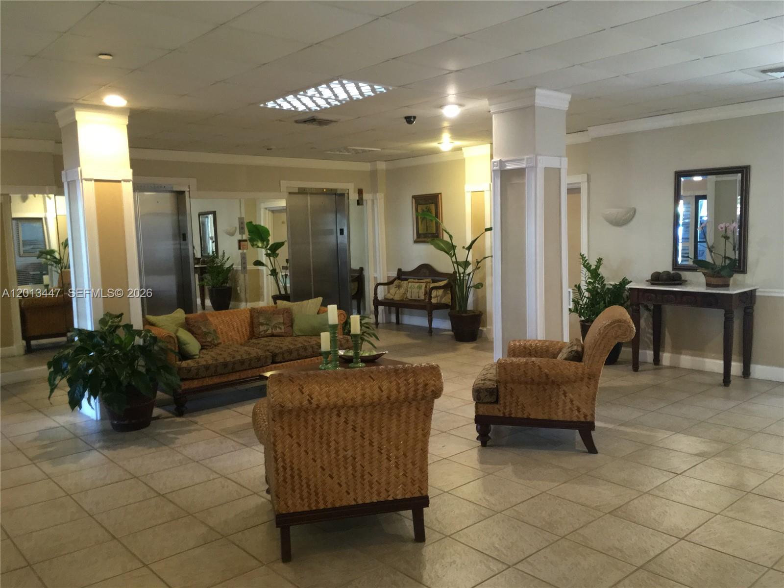 A lobby area features wicker furniture, tiled floors, potted plants, and two stainless steel elevators — 77 Crandon Blvd # 2E, Key Biscayne FL 33149, KEY BISCAYNE, FL