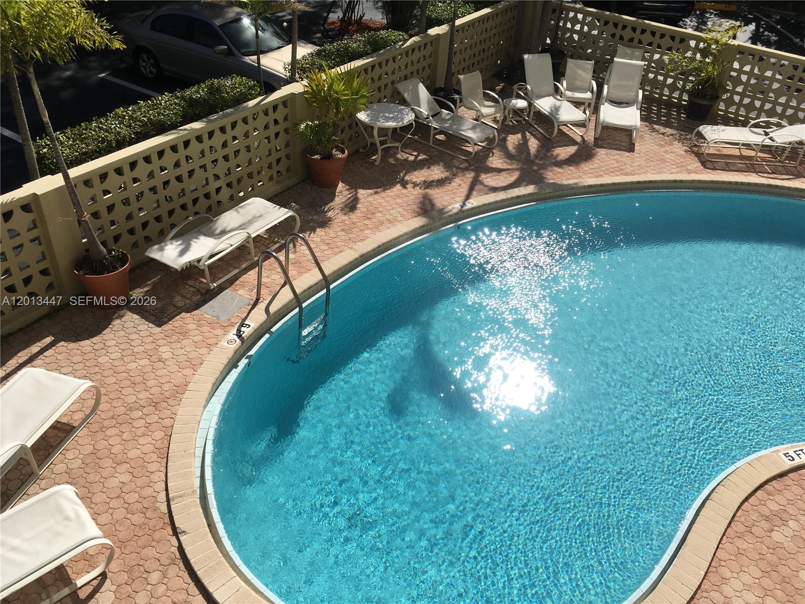 An outdoor swimming pool is surrounded by a paved deck with lounge chairs and planters — 77 Crandon Blvd # 2E, Key Biscayne FL 33149, KEY BISCAYNE, FL