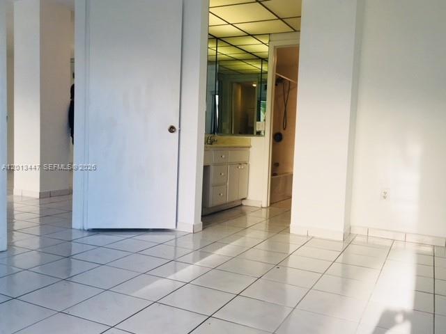 A room with white tiled floors leads to a bathroom with a vanity and mirror — 77 Crandon Blvd # 2E, Key Biscayne FL 33149, KEY BISCAYNE, FL