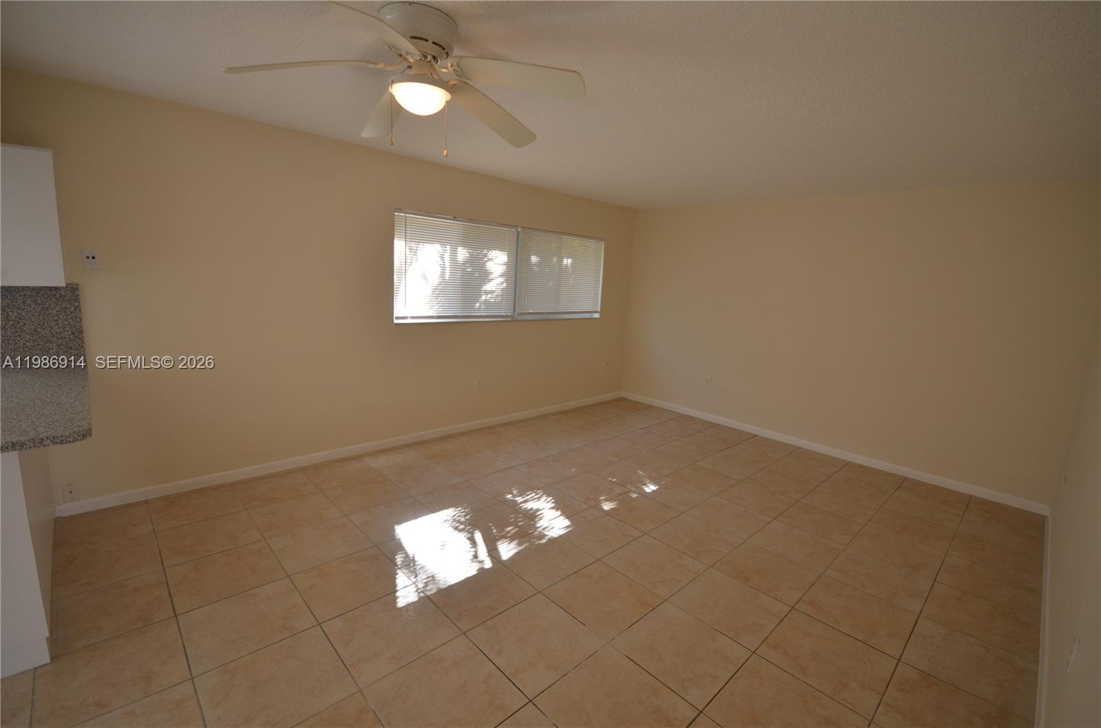 An empty room features beige tile flooring, light-colored walls, and a ceiling fan — 7626 NE 6th Ct # 1, Miami FL 33138, MIAMI, FL