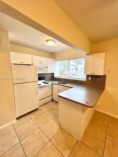 A kitchen features white cabinets, a white refrigerator, a stove, and a breakfast bar — 7626 NE 6th Ct # 1, Miami FL 33138, MIAMI, FL