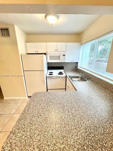 A kitchen features white cabinets, a white refrigerator, a white stove, and speckled countertops — 7626 NE 6th Ct # 1, Miami FL 33138, MIAMI, FL