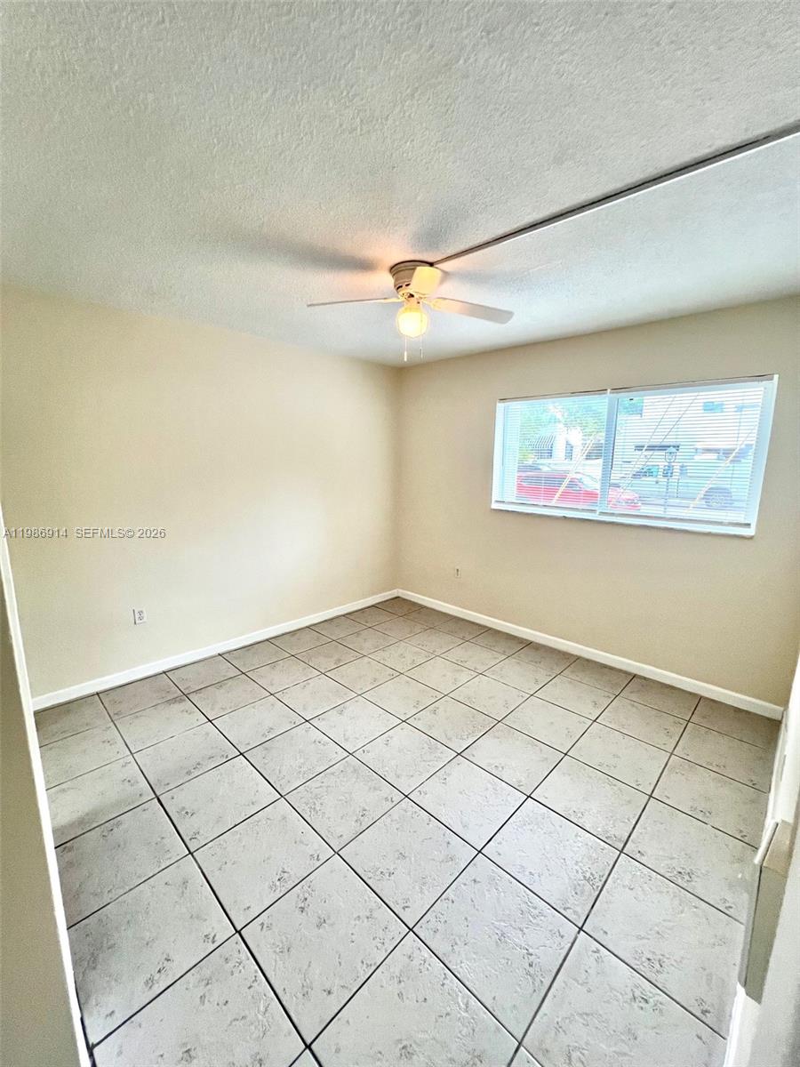 An empty room features beige walls, a ceiling fan, and light-colored square floor tiles — 7626 NE 6th Ct # 1, Miami FL 33138, MIAMI, FL