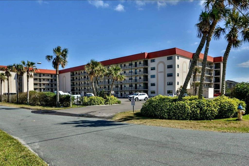 A multi-story apartment building with a red roof and palm trees in the foreground — 4301 S ATLANTIC AVENUE UNIT 2110, NEW SMYRNA BEACH, FL