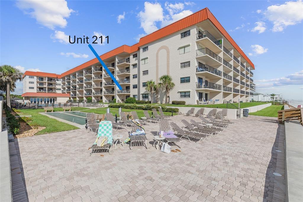 An exterior view of a multi-story apartment building with a pool deck and lounge chairs — 4301 S ATLANTIC AVENUE UNIT 2110, NEW SMYRNA BEACH, FL
