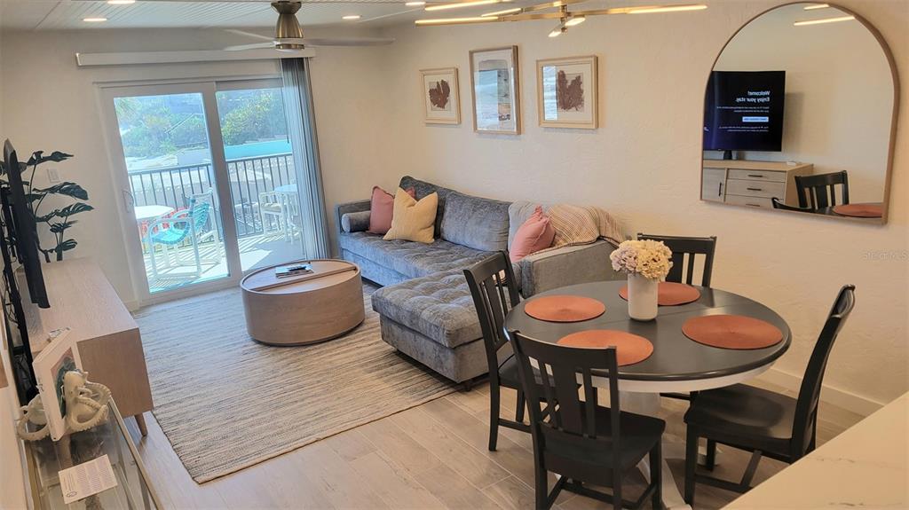 A living and dining area features a gray sectional sofa, round table, and balcony access — 4301 S ATLANTIC AVENUE UNIT 2110, NEW SMYRNA BEACH, FL