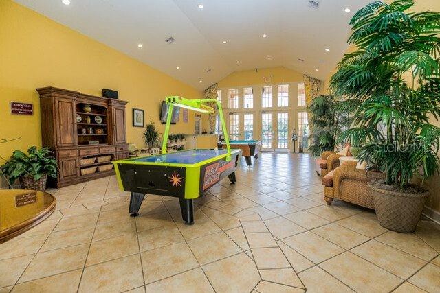 A brightly lit community room features a central air hockey table and tile flooring — 2608 LODI CIRCLE UNIT 103, KISSIMMEE, FL