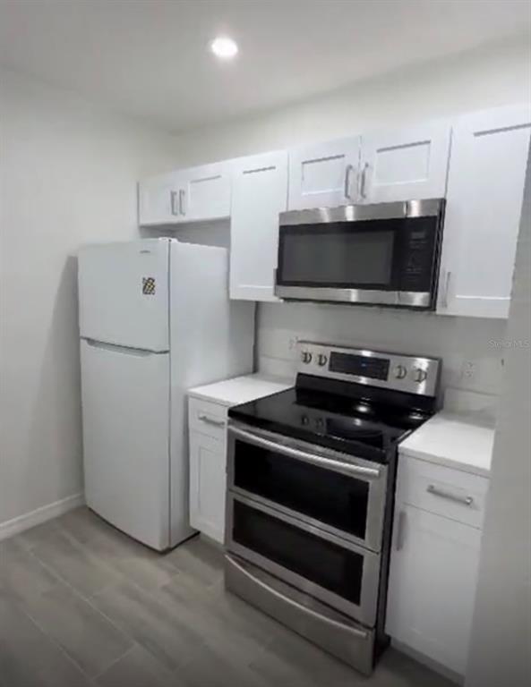 A kitchen features white cabinets, stainless steel appliances, and light-colored tile flooring — 2608 LODI CIRCLE UNIT 103, KISSIMMEE, FL