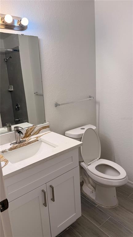 A bathroom features a white vanity with a marble countertop, a mirror, and a toilet — 2608 LODI CIRCLE UNIT 103, KISSIMMEE, FL