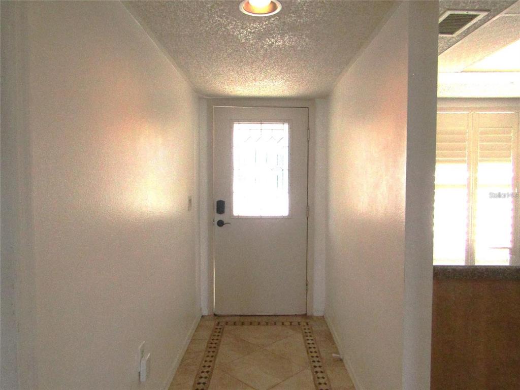 A hallway with white walls, a tiled floor, and a white door with a window — 4434 WEYBRIDGE UNIT 81, SARASOTA, FL