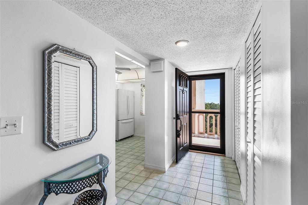 An entryway with tiled floors, a mirror, a console table, and an open exterior door — 1776 6TH STREET NW UNIT 807, WINTER HAVEN, FL