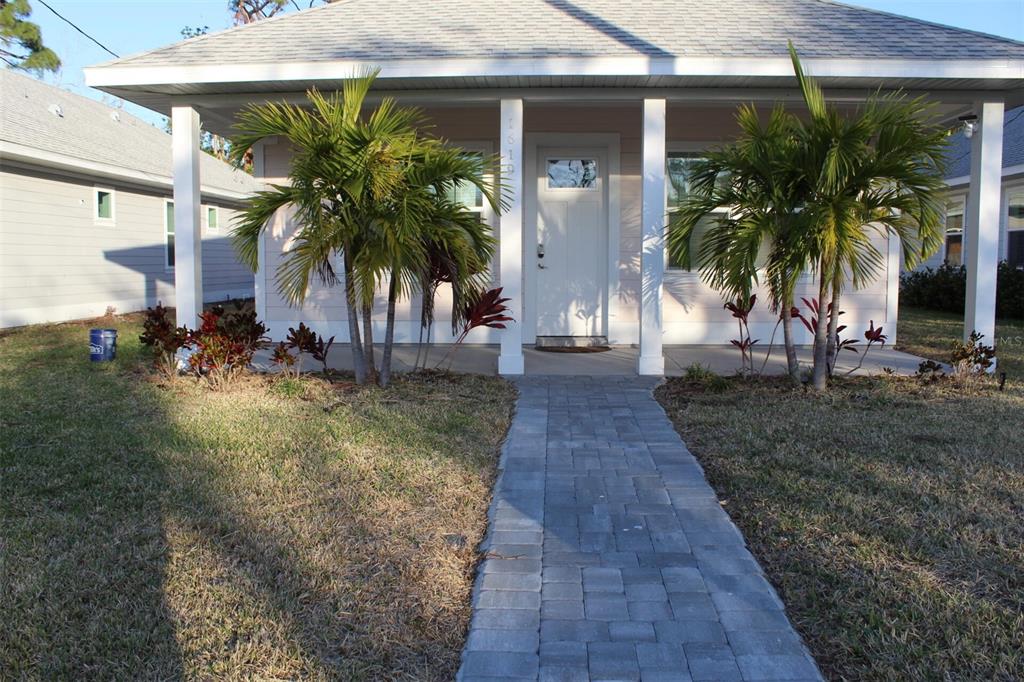 A front view of a single-story house with a covered porch, palm trees, and stone walkway — 1619 17TH STREET W, BRADENTON, FL