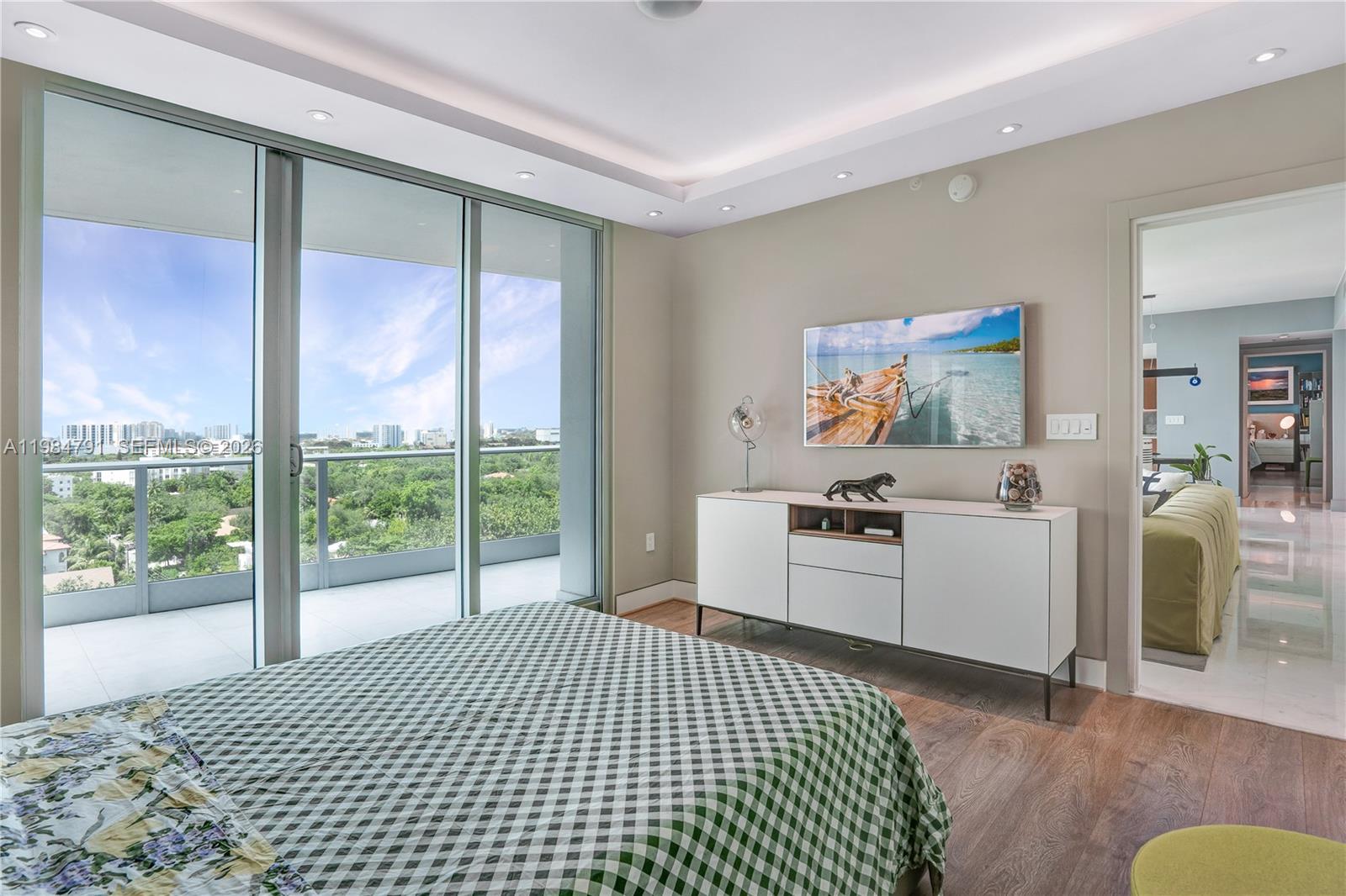 A bedroom features a green checkered bed, a white media console, and floor-to-ceiling balcony doors — 2627 S Bayshore Dr # 1408, Miami FL 33133, MIAMI, FL