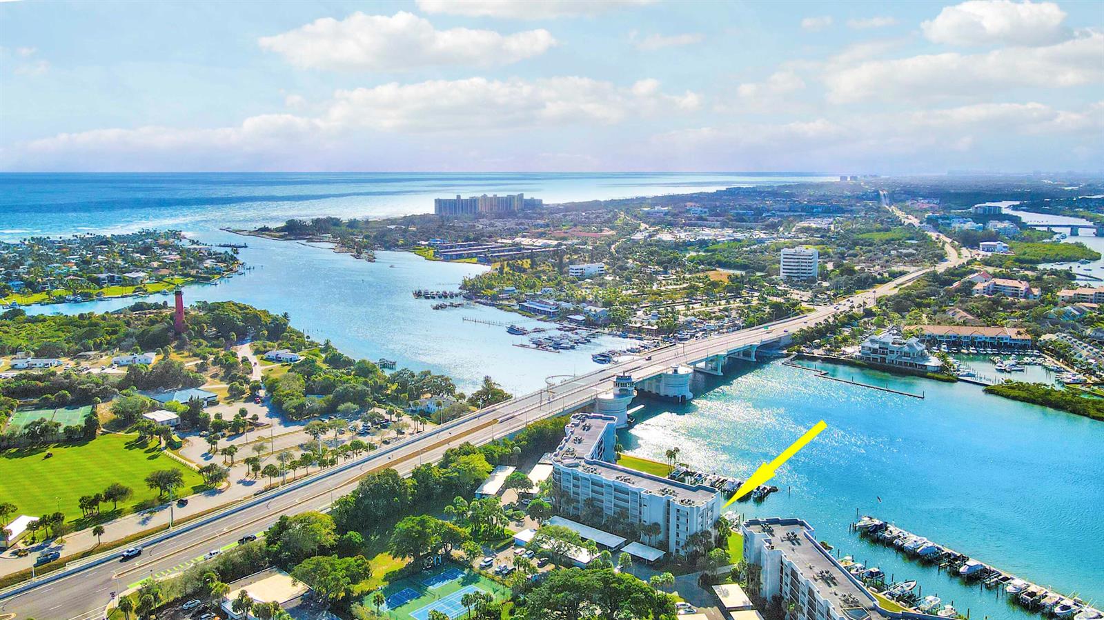 An aerial view shows a waterfront condominium building with a boat dock and nearby bridge — 1748 Jupiter Cove Drive # 417, Jupiter FL 33469, JUPITER, FL