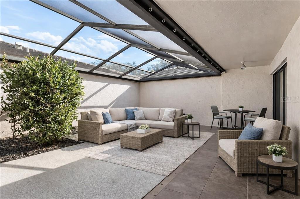 A covered patio features a sectional sofa, an armchair, and a dining set on tile — 3820 GLEN OAKS MANOR DRIVE, SARASOTA, FL