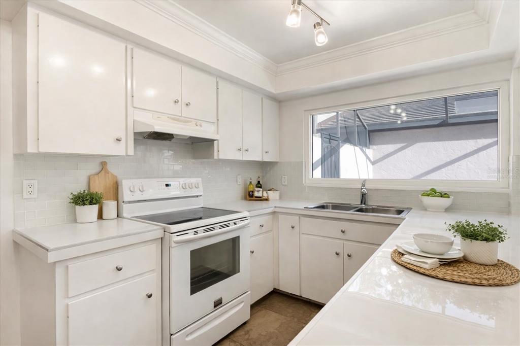 A white kitchen features white cabinets, a white electric range, and a double-basin sink — 3820 GLEN OAKS MANOR DRIVE, SARASOTA, FL