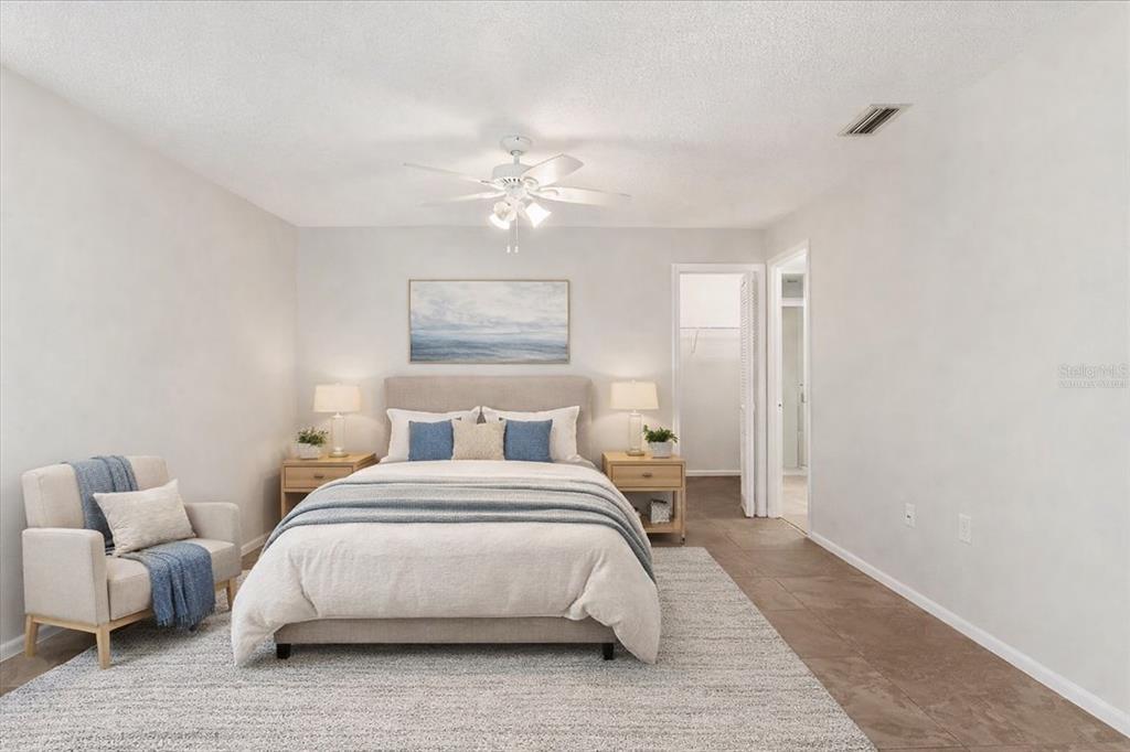A bedroom features a bed with blue accents, a side chair, and tile flooring — 3820 GLEN OAKS MANOR DRIVE, SARASOTA, FL