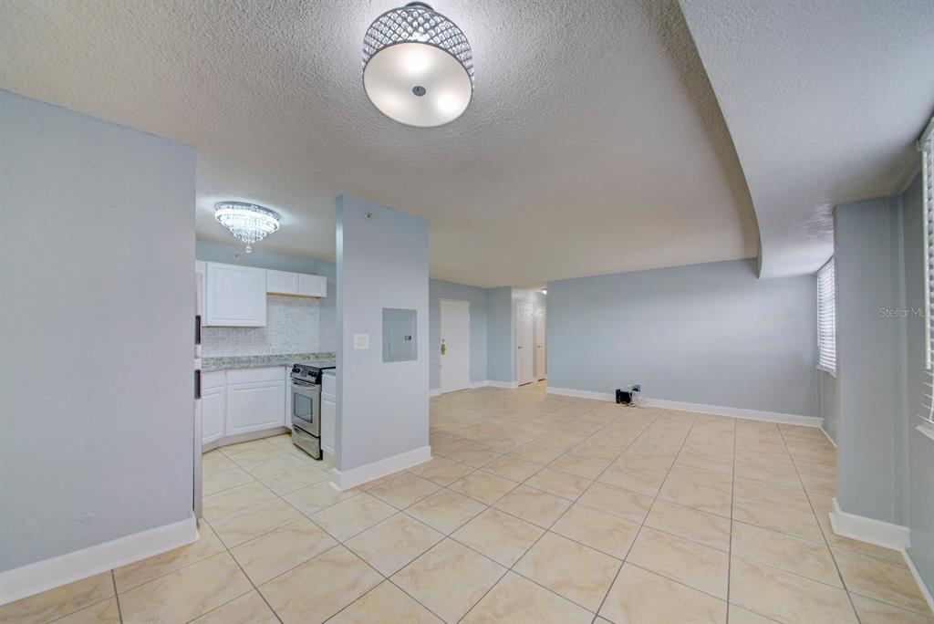 An open-concept living area with tiled floors leads into a small kitchen with white cabinets — 3315 58TH AVENUE S UNIT 306, ST PETERSBURG, FL