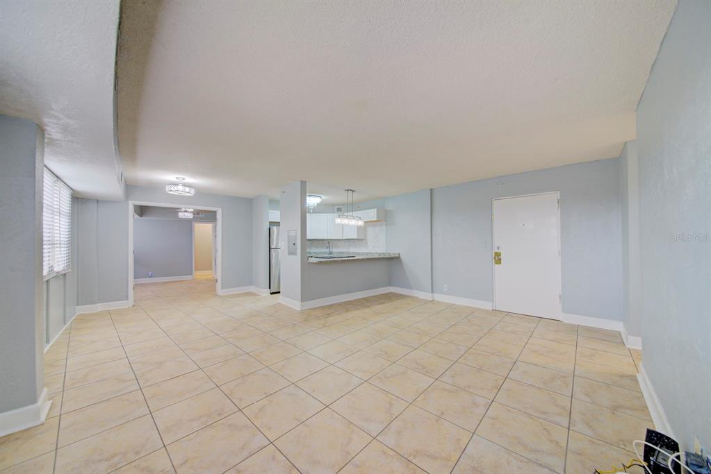 An open-concept living area features light blue walls, beige tile flooring, and a kitchen pass-through — 3315 58TH AVENUE S UNIT 306, ST PETERSBURG, FL