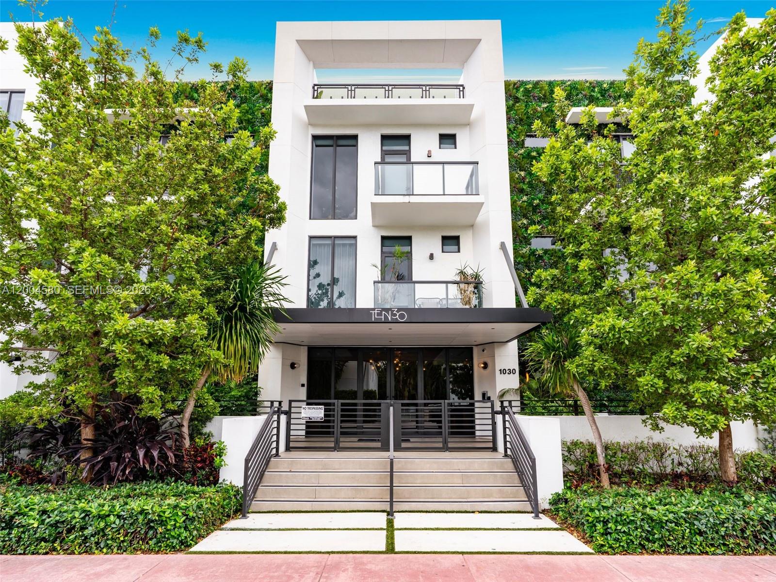 A modern white multi-story building features a gated entrance, balconies, and lush vertical greenery — 1030 15th St # 321, Miami Beach FL 33139, MIAMI BEACH, FL