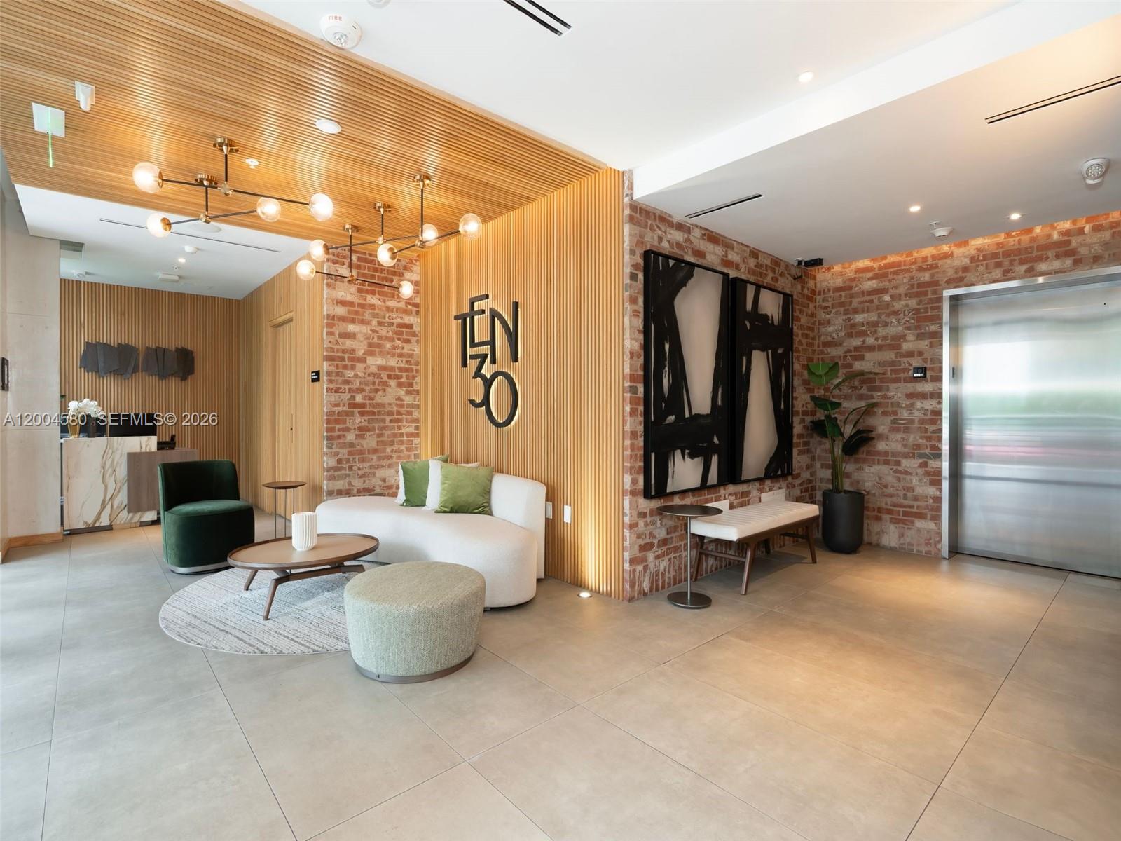 A modern lobby features wood-slat walls, exposed brick, a white sofa, and a metal elevator — 1030 15th St # 321, Miami Beach FL 33139, MIAMI BEACH, FL
