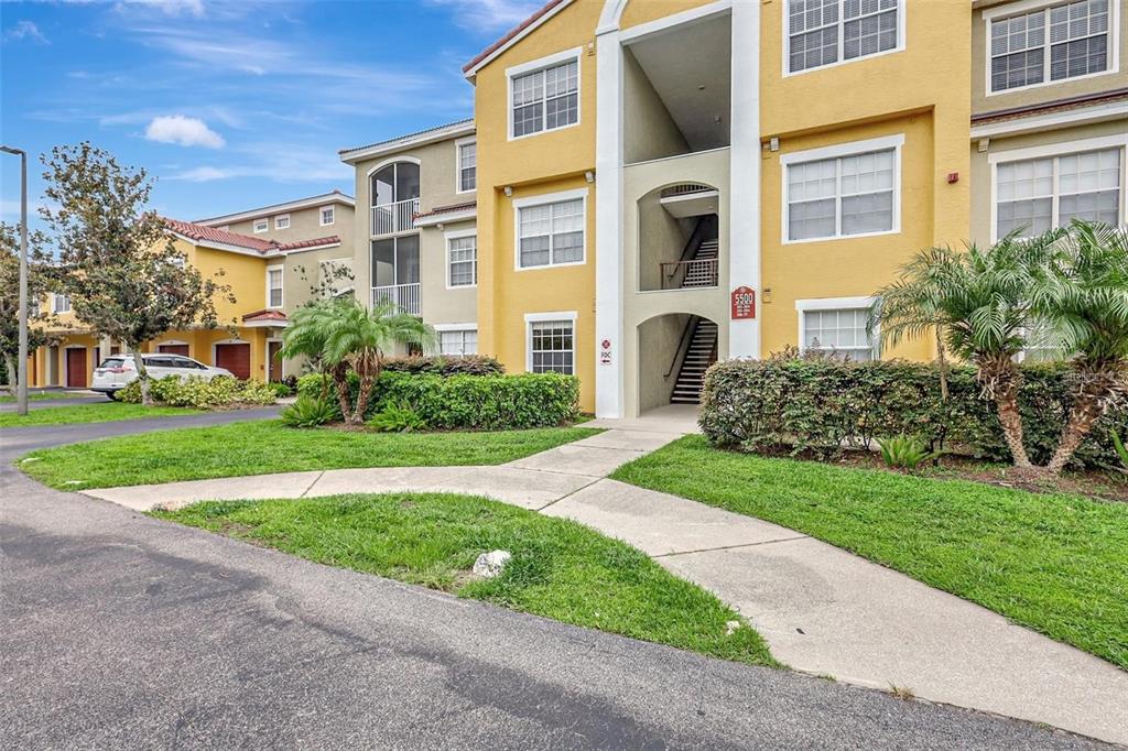 A multi-story yellow apartment building with a central staircase and a paved walkway — 5500 BENTGRASS DRIVE UNIT 6-301, SARASOTA, FL