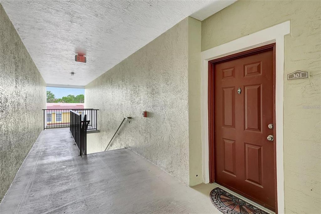 An exterior hallway leads to a brown apartment door marked with the number 301 — 5500 BENTGRASS DRIVE UNIT 6-301, SARASOTA, FL