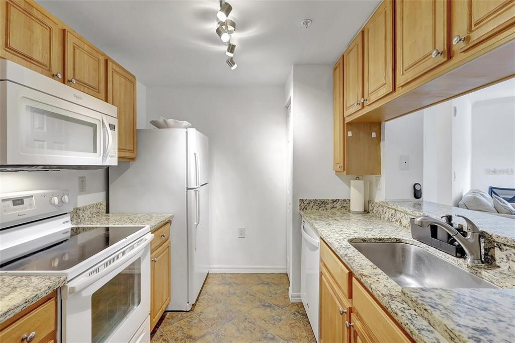 A kitchen with light wood cabinets, granite countertops, white appliances, and tile flooring — 5500 BENTGRASS DRIVE UNIT 6-301, SARASOTA, FL
