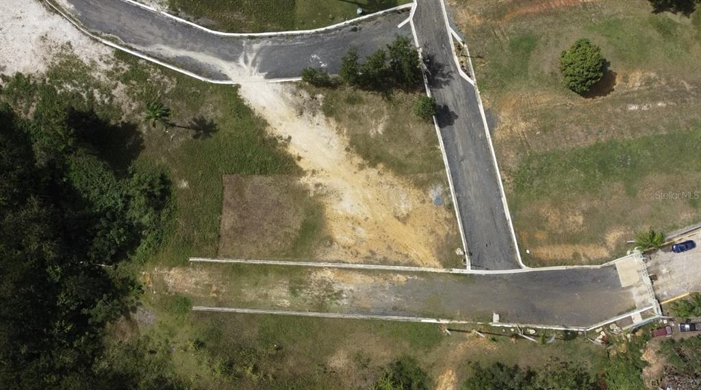 An aerial view shows a paved road intersection and undeveloped land with scattered trees — HACIENDA RIO LAJAS UNIT #1, DORADO, PR
