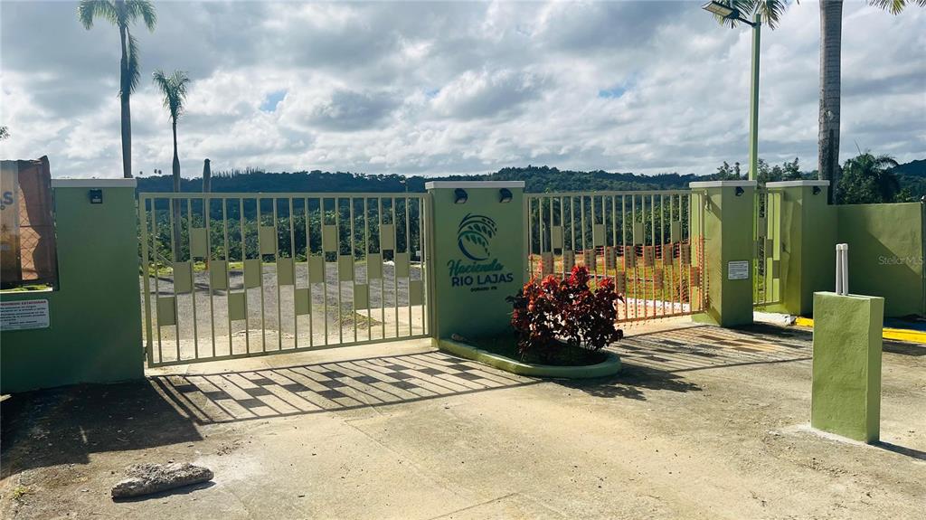 A gated entrance with a sign reading Hacienda Rio Lajas leads to a gravel driveway — HACIENDA RIO LAJAS UNIT #1, DORADO, PR