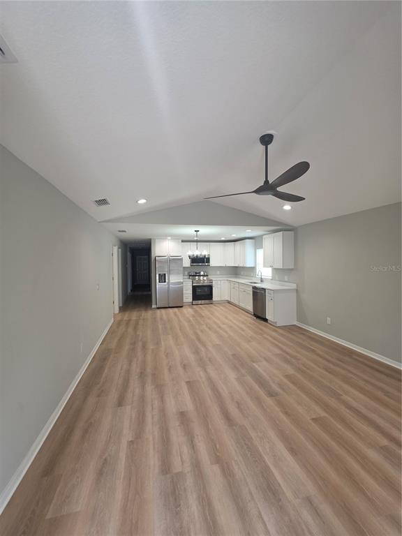 A kitchen with white cabinets and stainless steel appliances opens into a large living area — 851 AVENUE R NE, WINTER HAVEN, FL