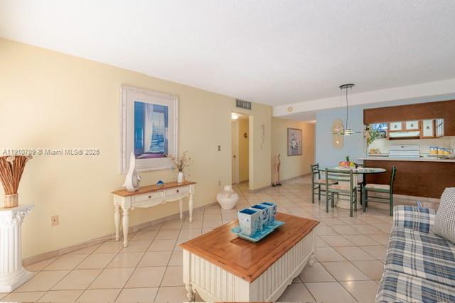A living room with tile floors, a wooden coffee table, and an open kitchen area — 1890 W 56th St # 1423, Hialeah FL 33012, HIALEAH, FL