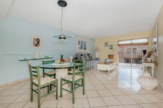A dining area with a glass table and green chairs sits beside a living room — 1890 W 56th St # 1423, Hialeah FL 33012, HIALEAH, FL