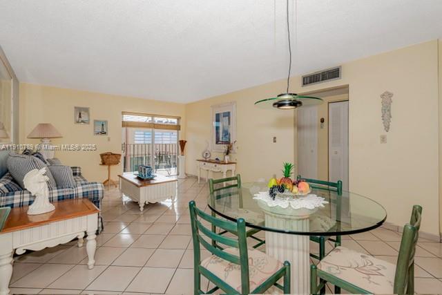 A dining area and living room with tile floors, a glass table, and balcony access — 1890 W 56th St # 1423, Hialeah FL 33012, HIALEAH, FL