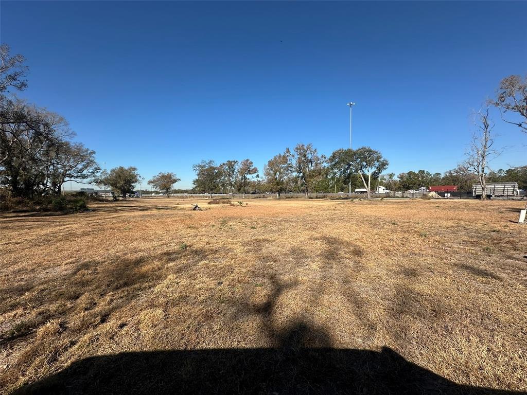 A wide, flat, grassy lot under a clear blue sky with trees in the background — 5257 EUREKA SPRINGS ROAD, TAMPA, FL