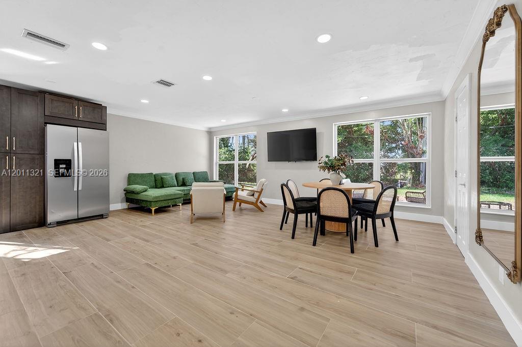 An open-concept living and dining area features light wood floors and a green sofa — 756 Cinnamon Rd, North Palm Beach FL 33408, NORTH PALM BEACH, FL