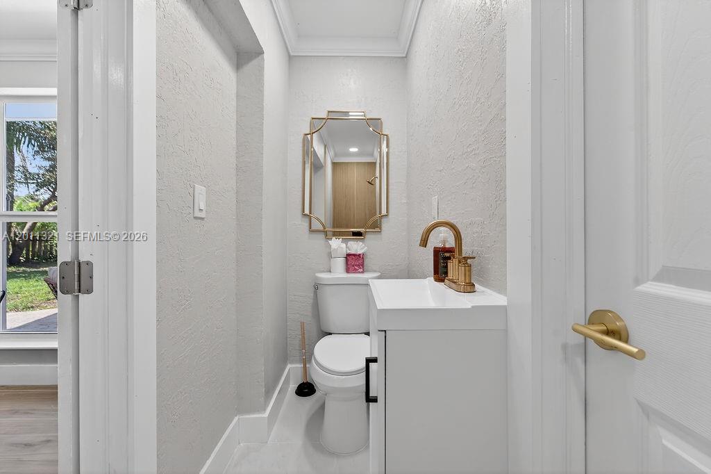 A small bathroom features a white vanity, a toilet, and a gold-framed mirror — 756 Cinnamon Rd, North Palm Beach FL 33408, NORTH PALM BEACH, FL