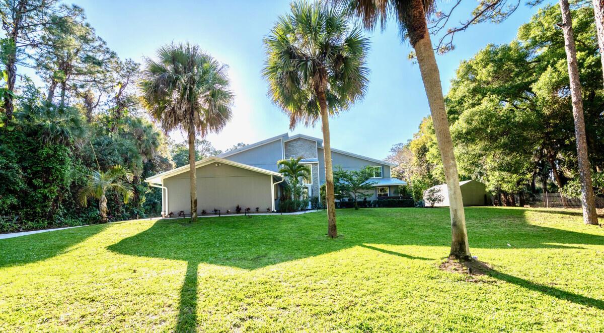 A two-story house with a gray exterior sits on a large, grassy lawn with palms — 16887 97th Way N, Jupiter FL 33478, JUPITER, FL