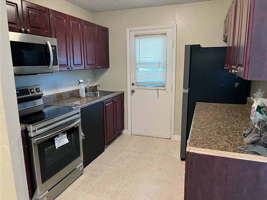 A kitchen features dark wood cabinets, stainless steel appliances, and brown granite countertops — 400 NW 65th Avenue # 209, Margate FL 33063, MARGATE, FL